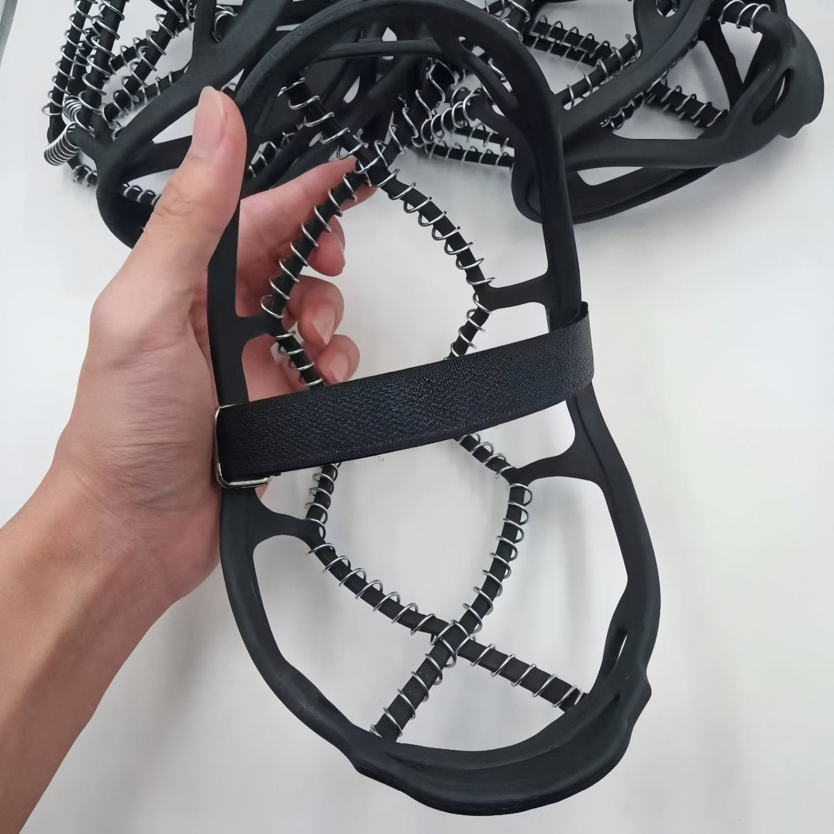 Hand stretching one ice grip to show its size and the coil cords