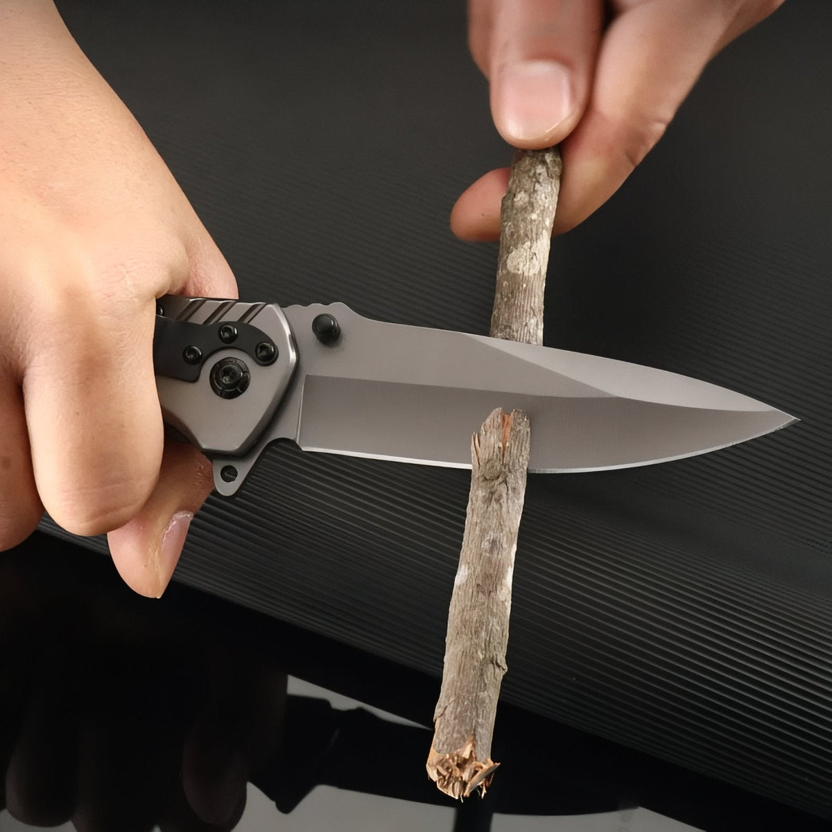Hand whittling a stick with the open folding knife