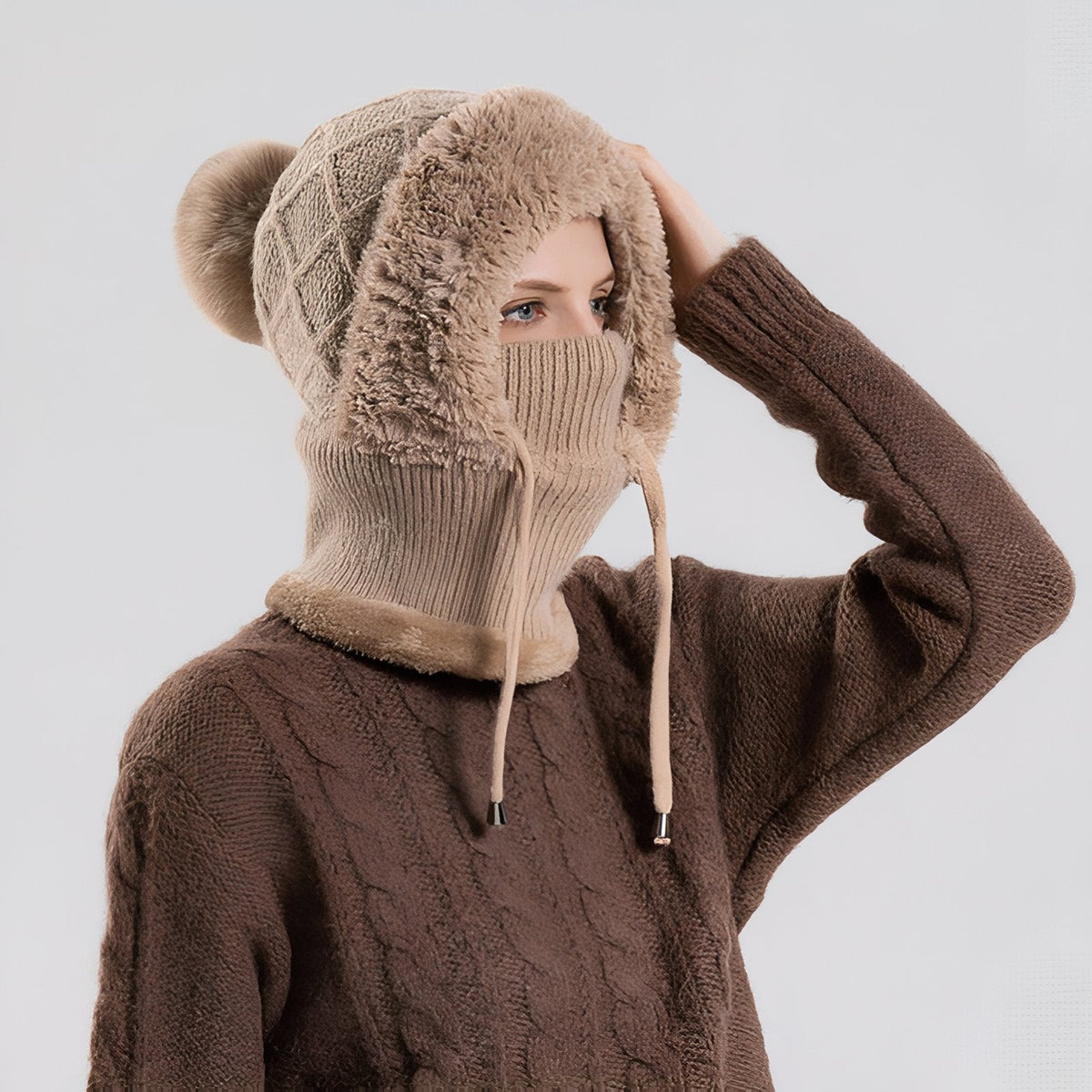 Side view of a woman in the brown balaclava hood, mask up and drawcords hanging at the sides