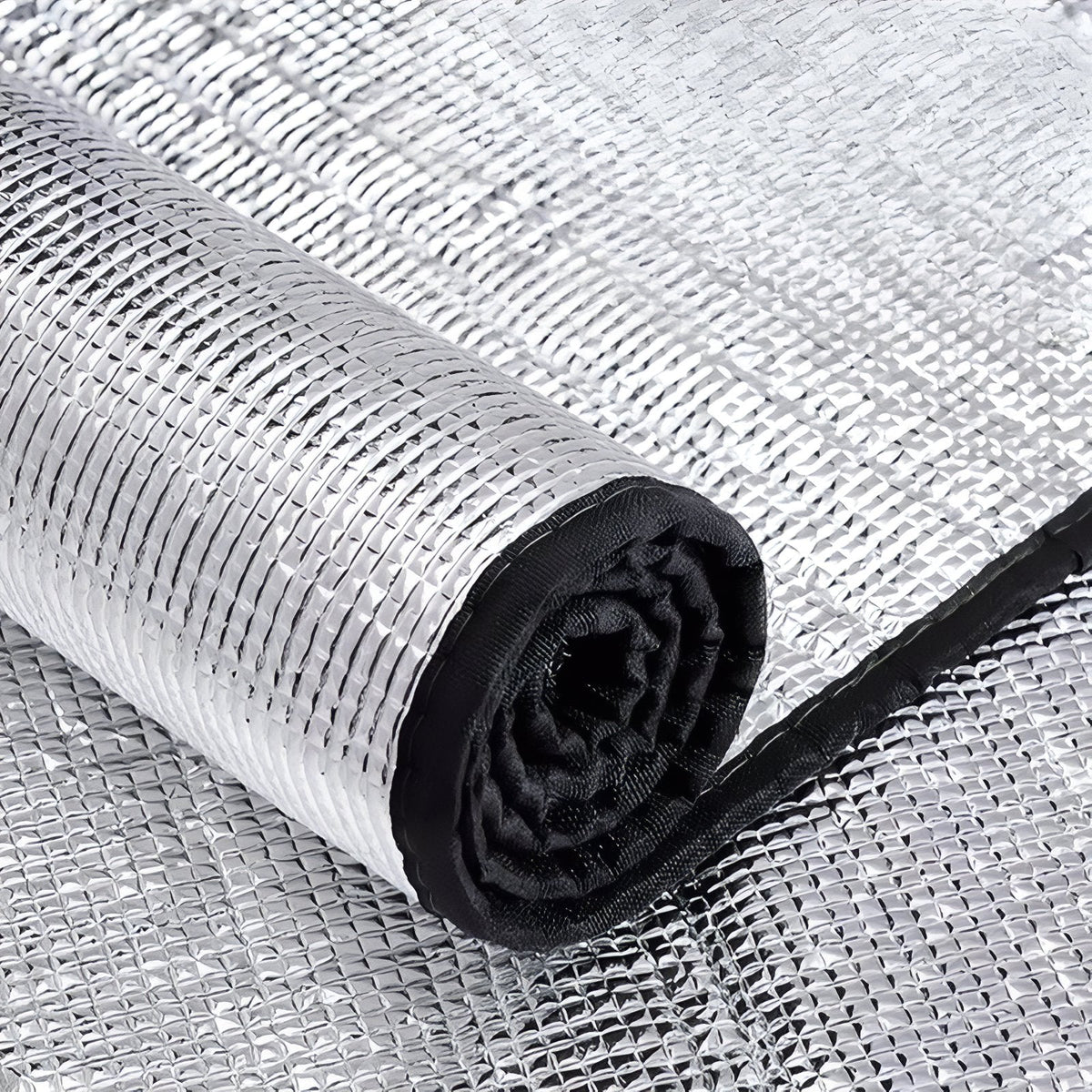 Close-up of the foil foam mat rolled up, showing the black fabric-bound edge and the quilted foil surface