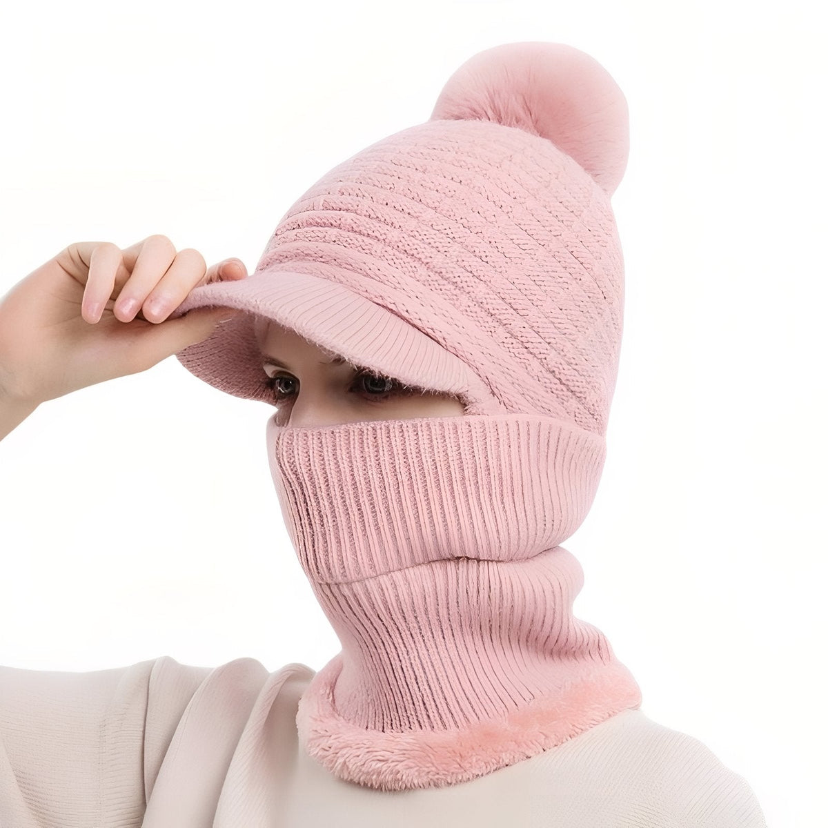 Powder pink brim beanie with pompom, the neck warmer pulled up over the face