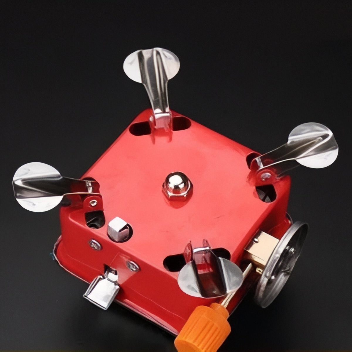 Red stove from below with its four legs and supports folded, orange knob at the side