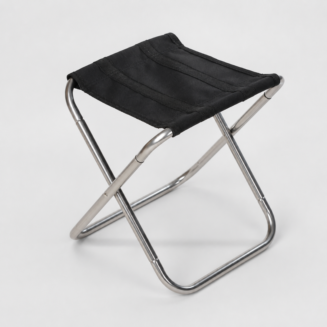 A folding stool with a brushed silver-grey frame and a plain black canvas seat, standing on a light grey background.