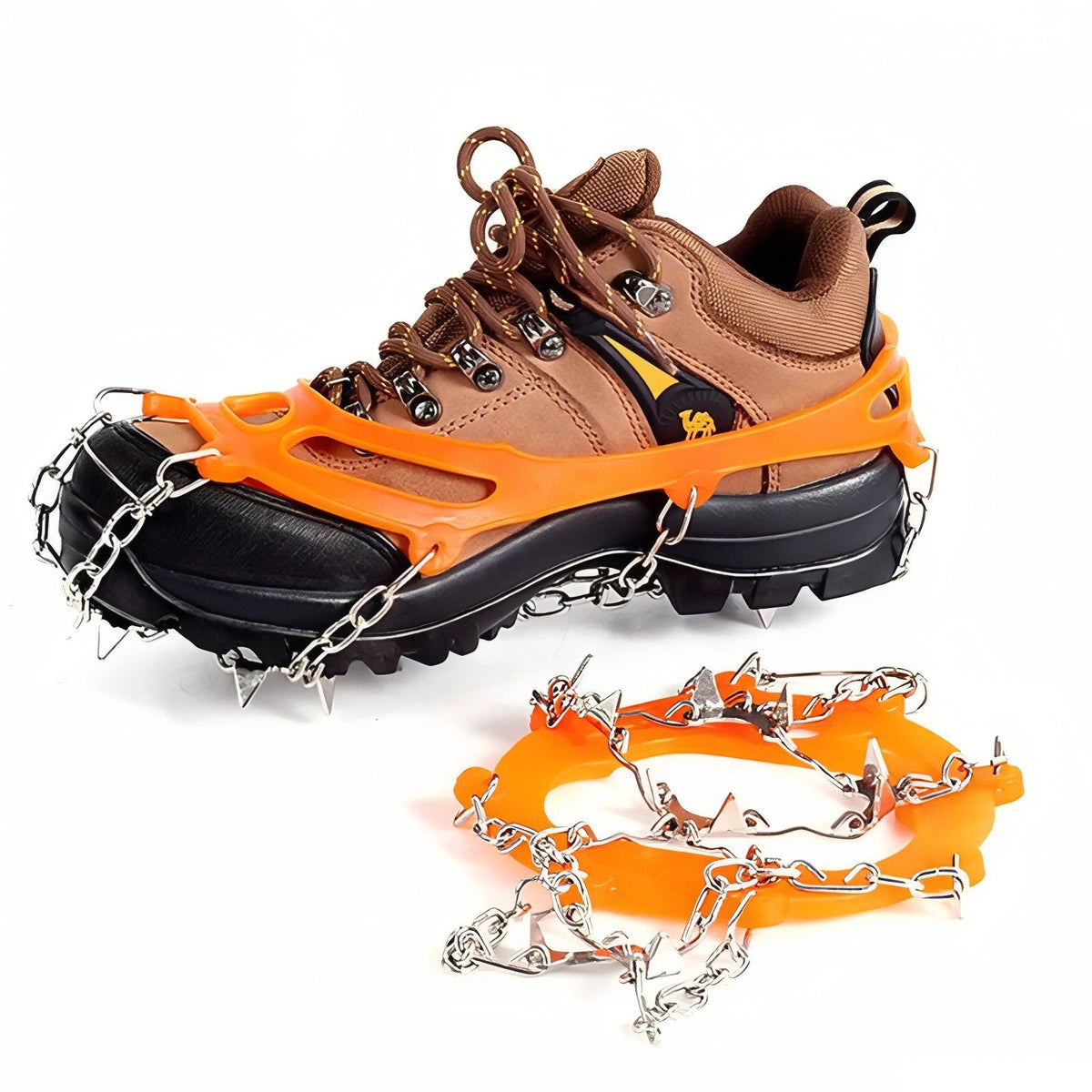One orange chain crampon fitted over a brown hiking boot and a second lying loose beside it, chain side up