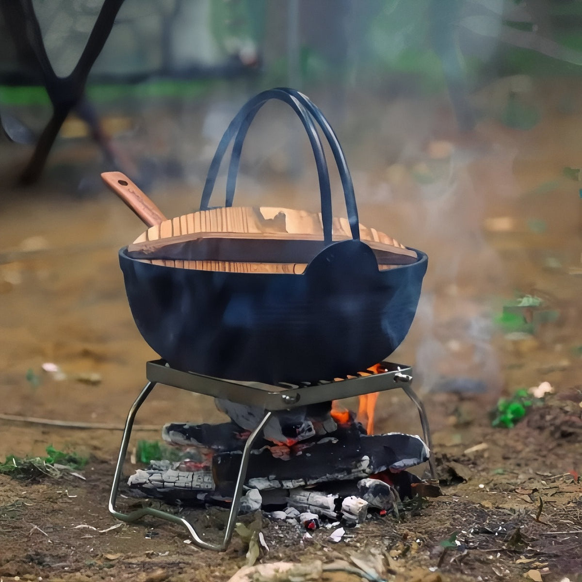 The grill stand holding a cast iron pot over a small campfire