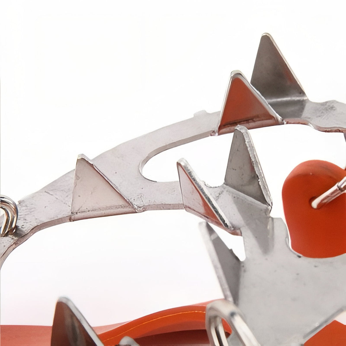 Close-up of the pointed stainless steel spikes and a linking ring on the orange harness
