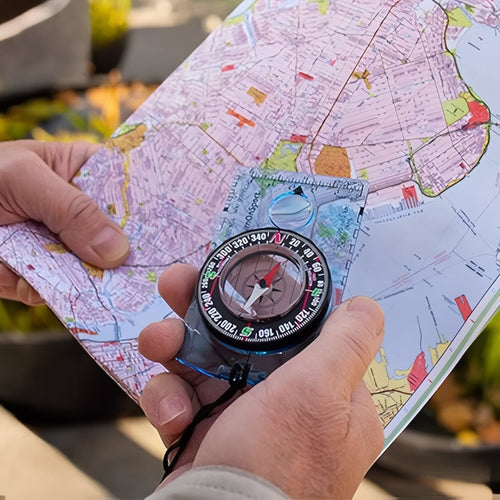 Hand holding the clear baseplate compass over a folded street map