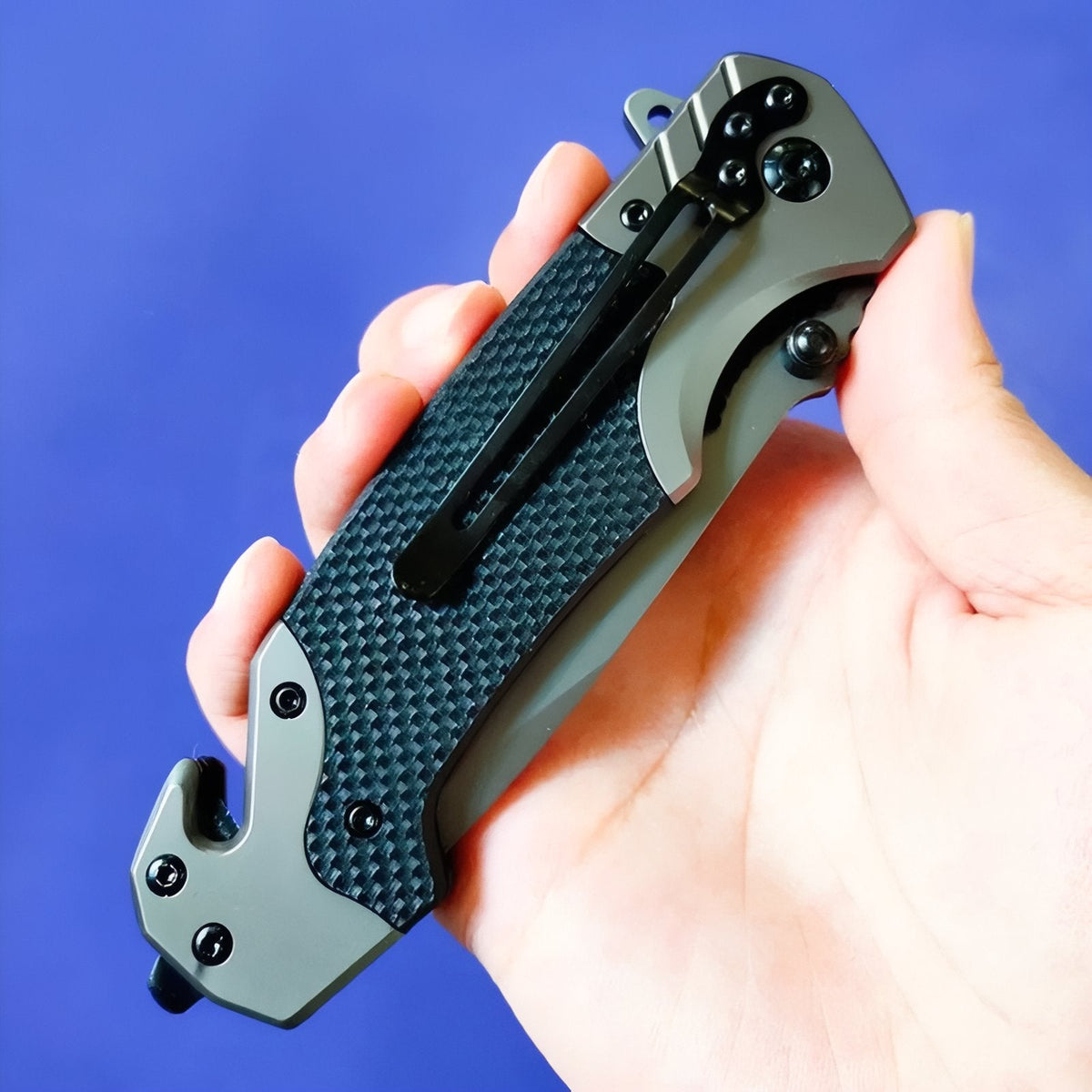 Closed folding knife in a hand showing the pocket clip and the strap cutter notch