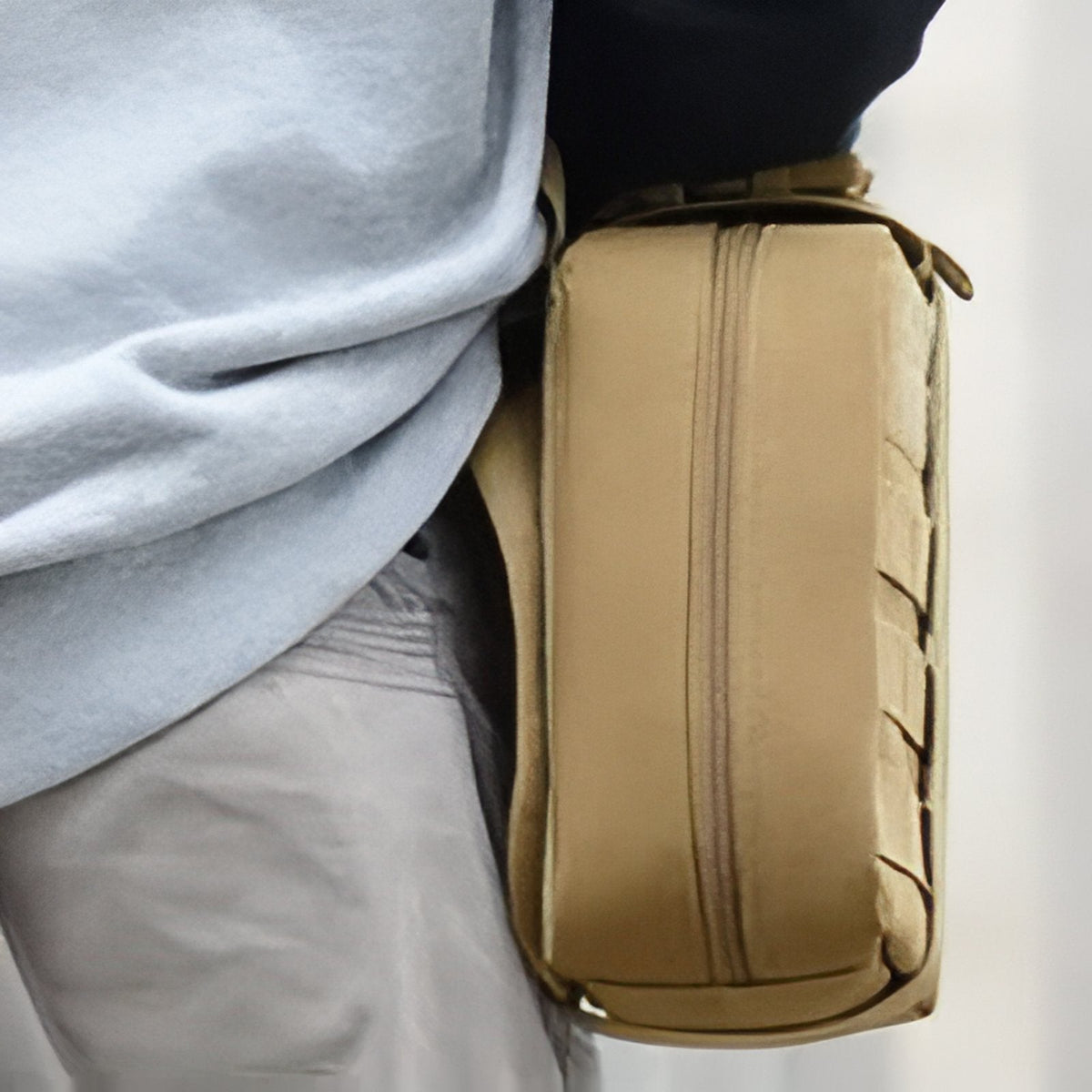 Khaki first aid pouch hanging at the side of a person's waist