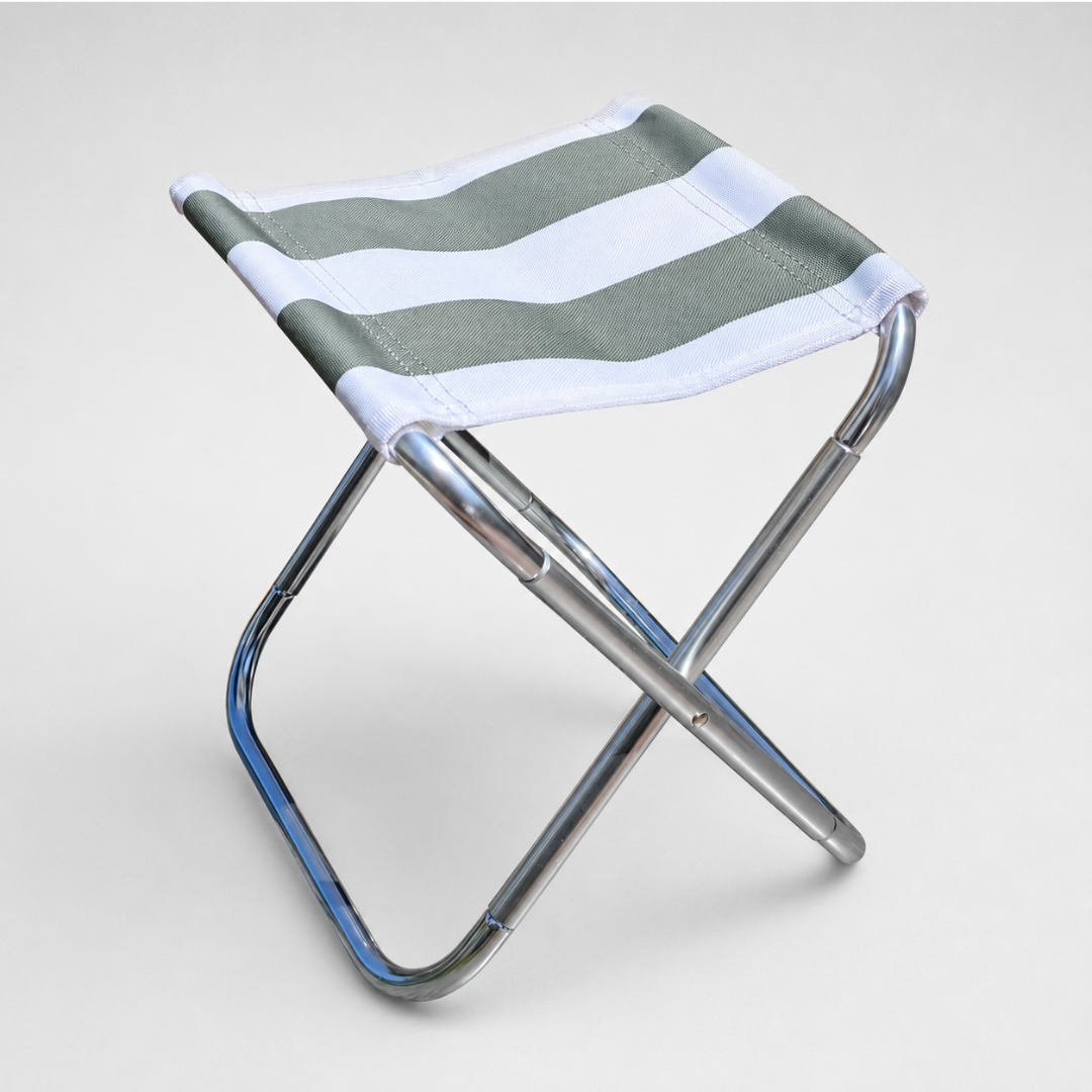 A folding camp stool with a silver aluminium frame and a green and white striped canvas seat, on a plain grey studio background.