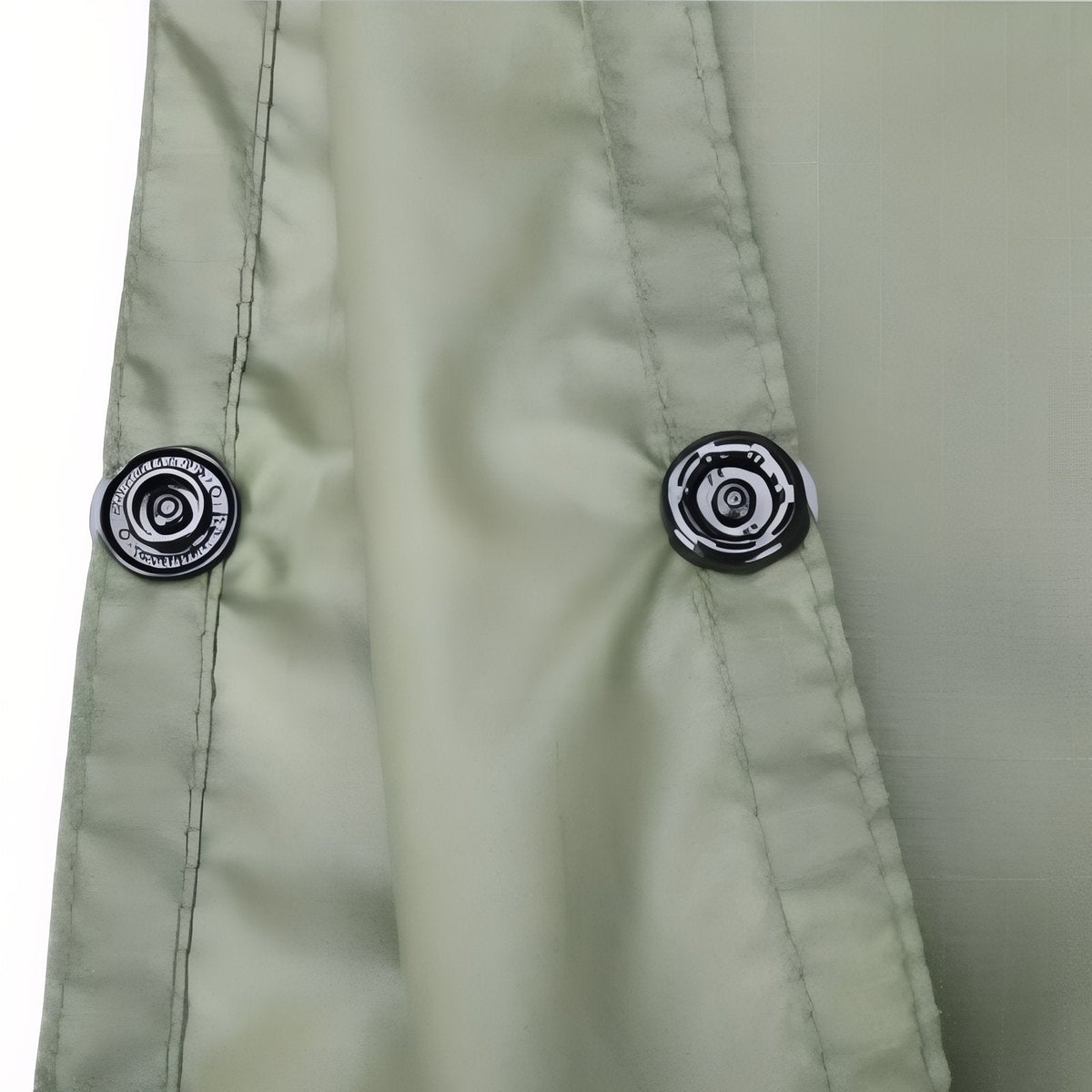 Close-up of two press snaps along the side edge of the olive green poncho