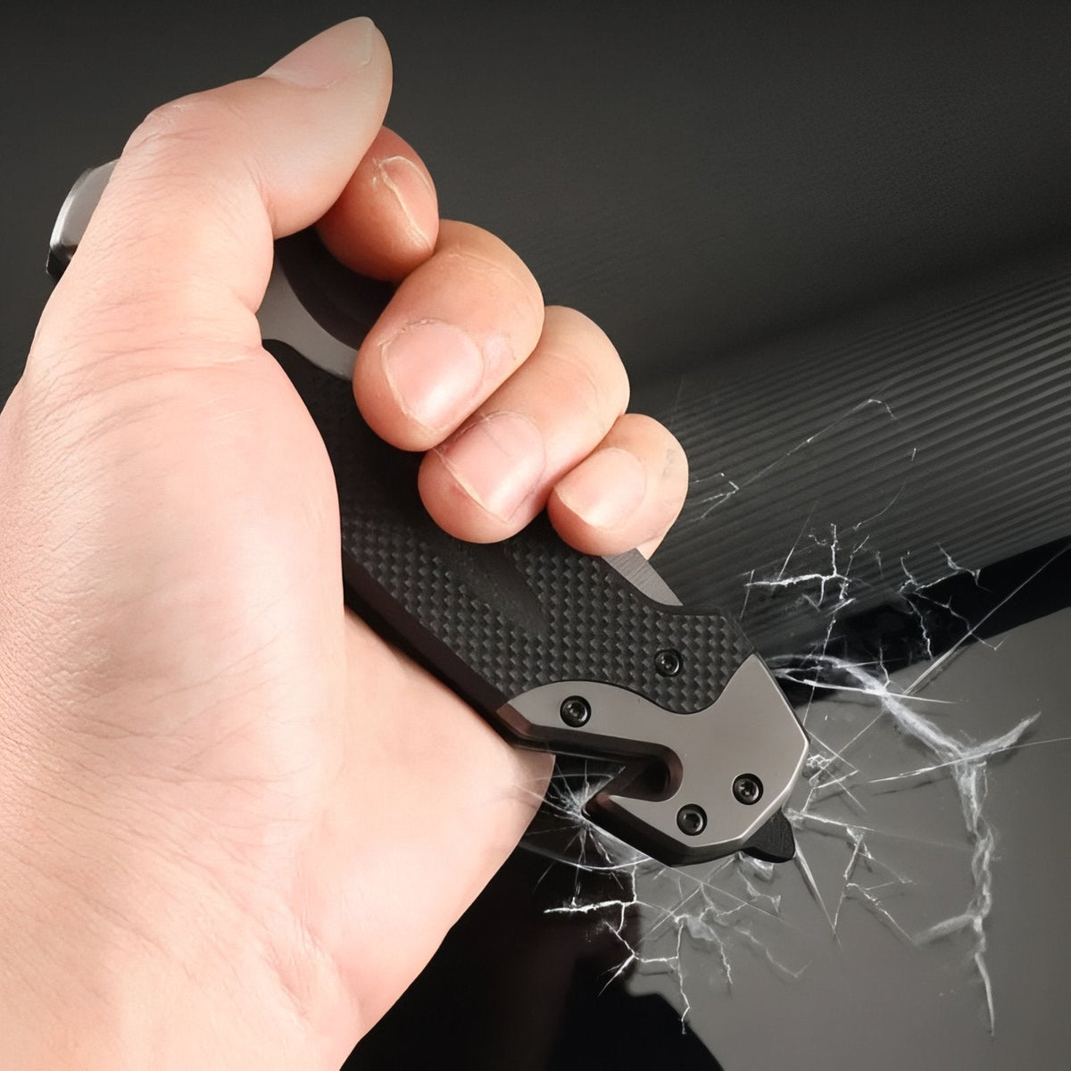 Hand gripping the closed knife with the glass breaker at the butt against a cracked pane