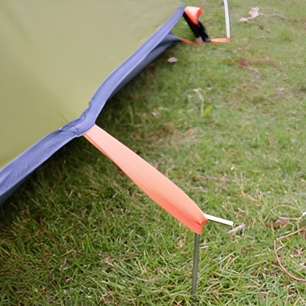 Webbing corner tab held down by a tent peg