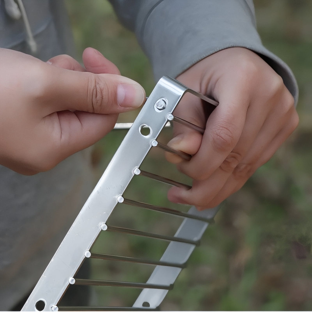 Hands folding out a leg of the grill stand
