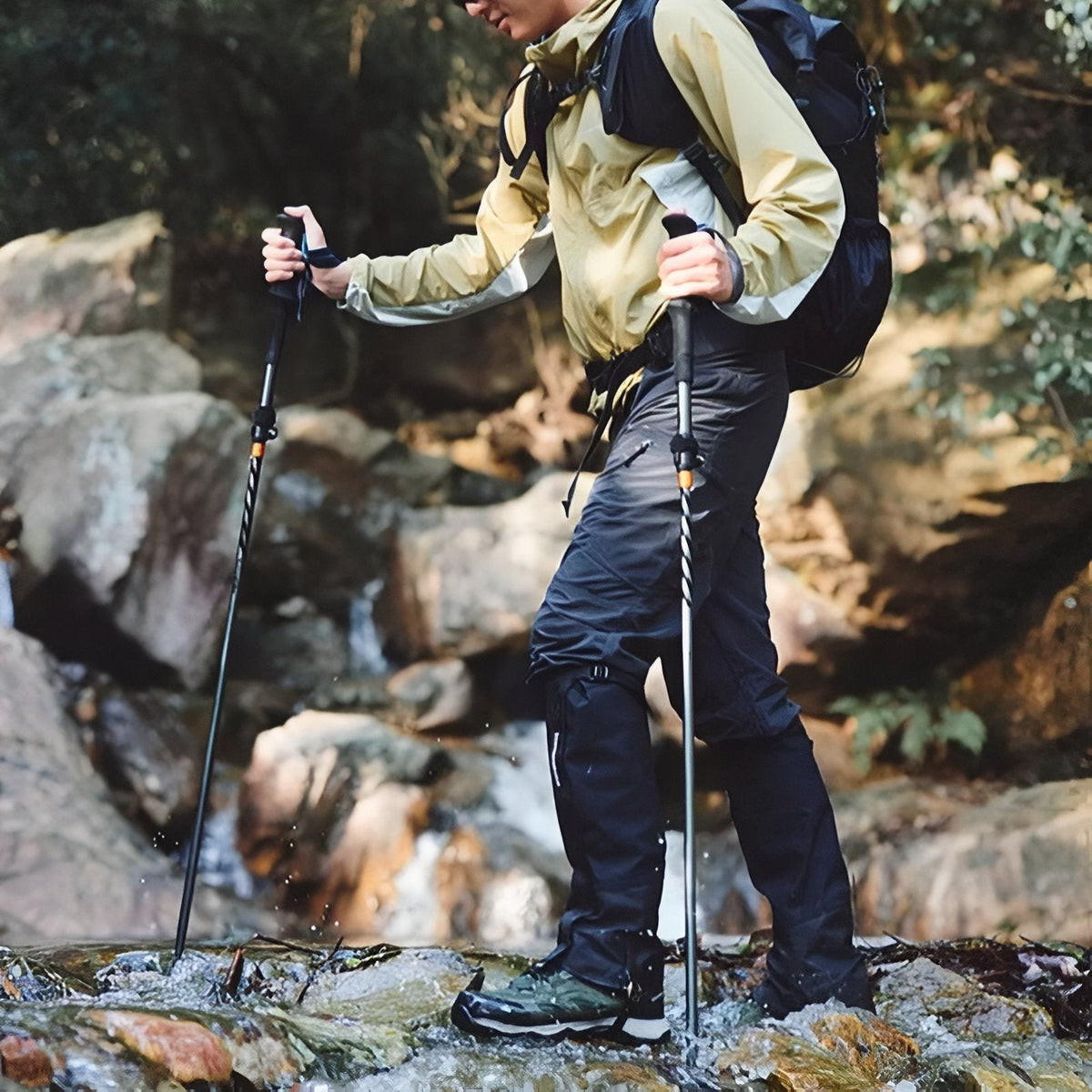 Walker using the trekking poles on wet rocks by a stream
