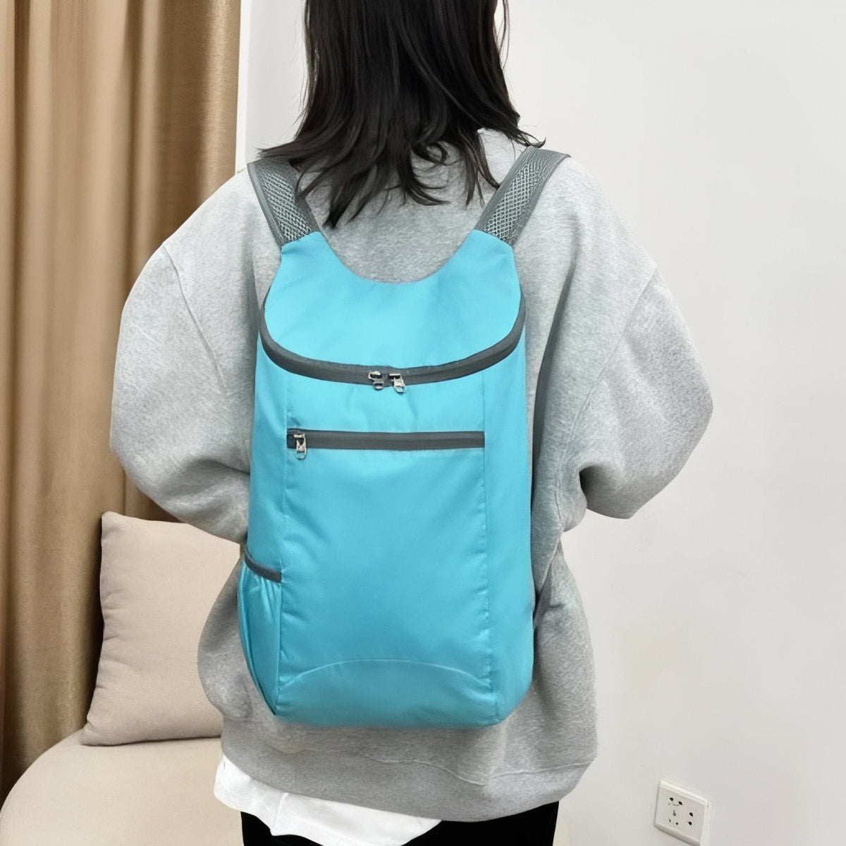 Woman wearing the sky blue packable daypack on both shoulders, back view
