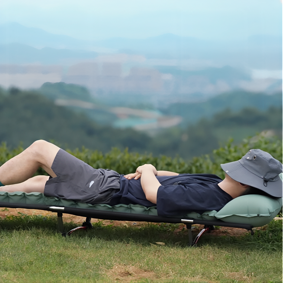 Man resting on the sage green mat laid on a camp bed outdoors