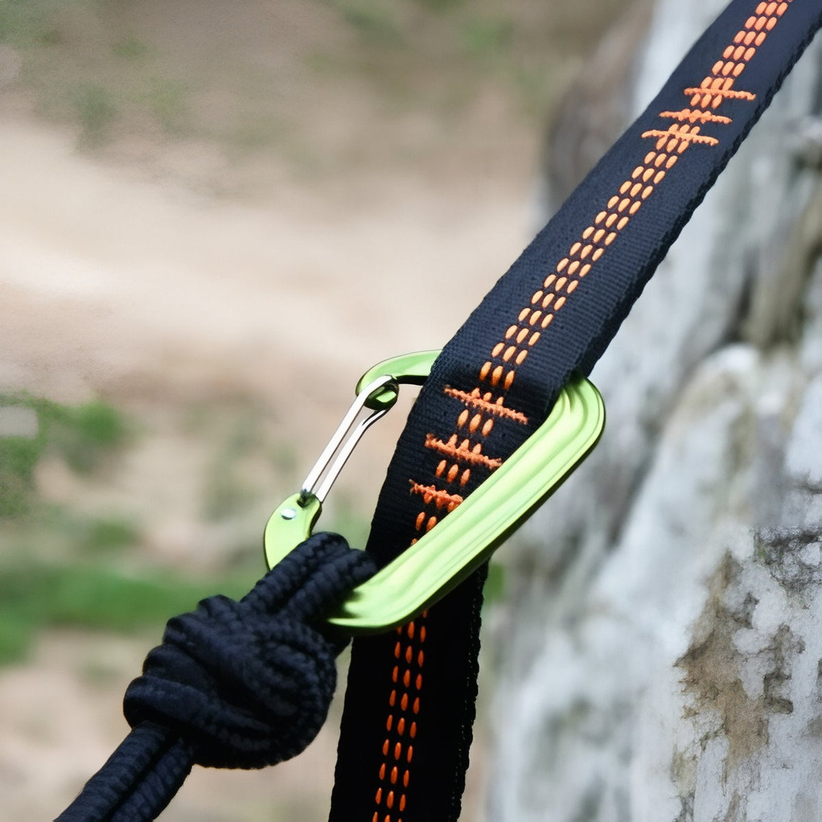 Close-up of a sewn loop on the black and orange strap with a hammock carabiner clipped in