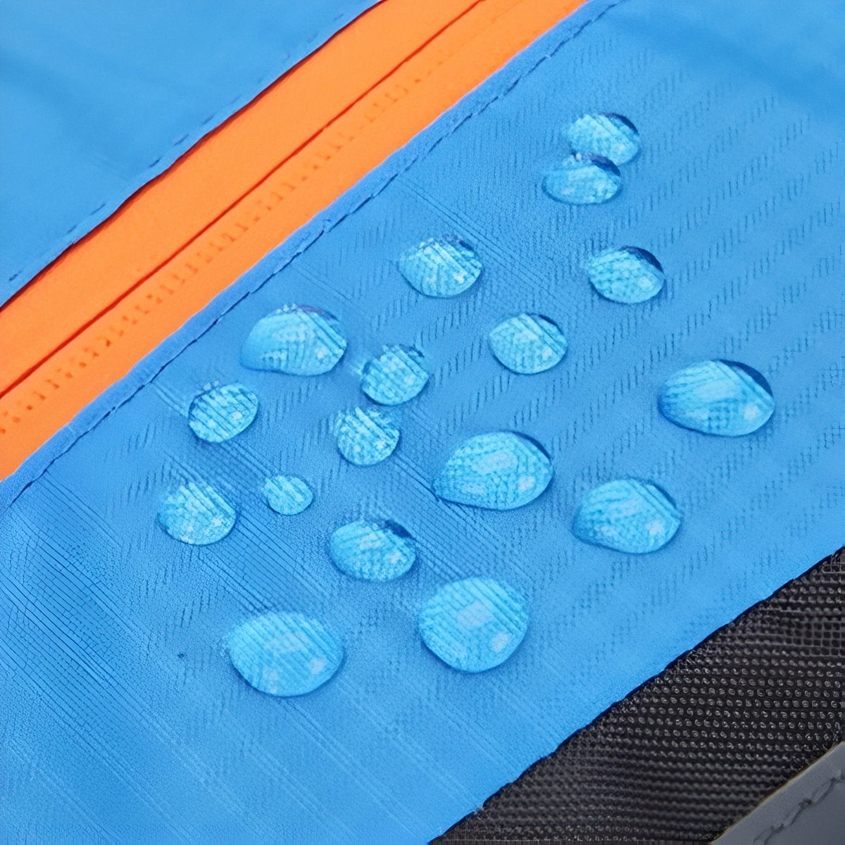 Close-up of water droplets beading on the sky blue ripstop fabric beside an orange zip
