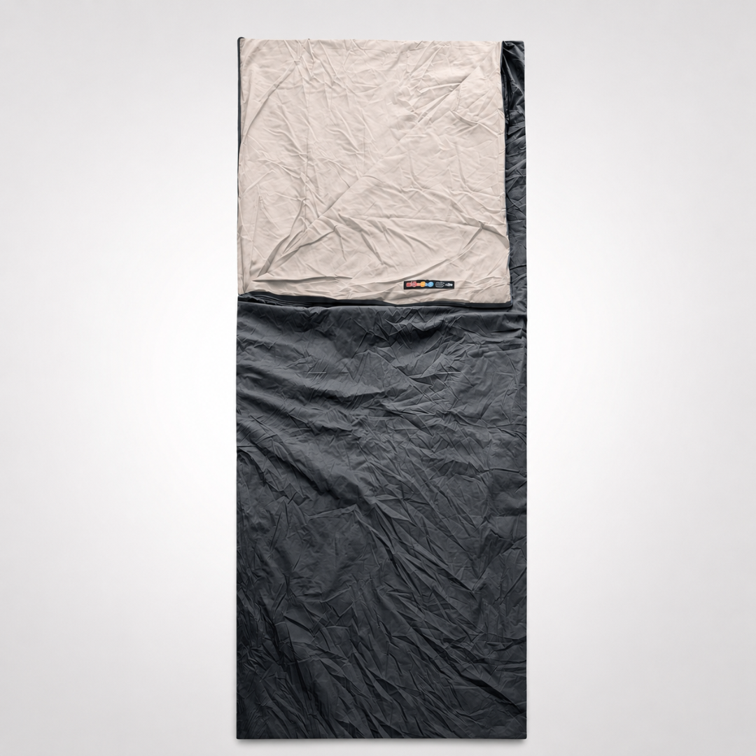 A charcoal black envelope sleeping bag laid flat, its cream lining folded back at the head