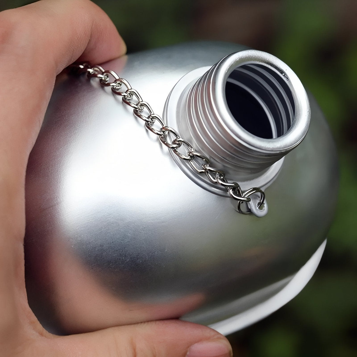 A hand holding the canteen, showing the screw cap on its chain