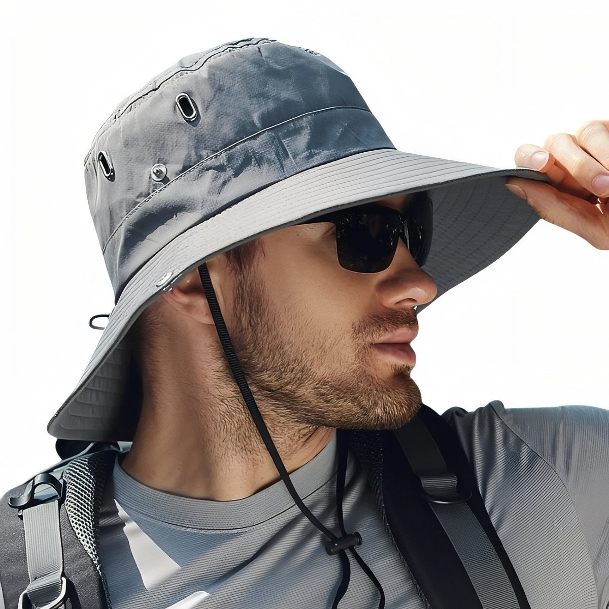 Man holding the brim of the grey wide-brim hiking hat, chin cord under his chin