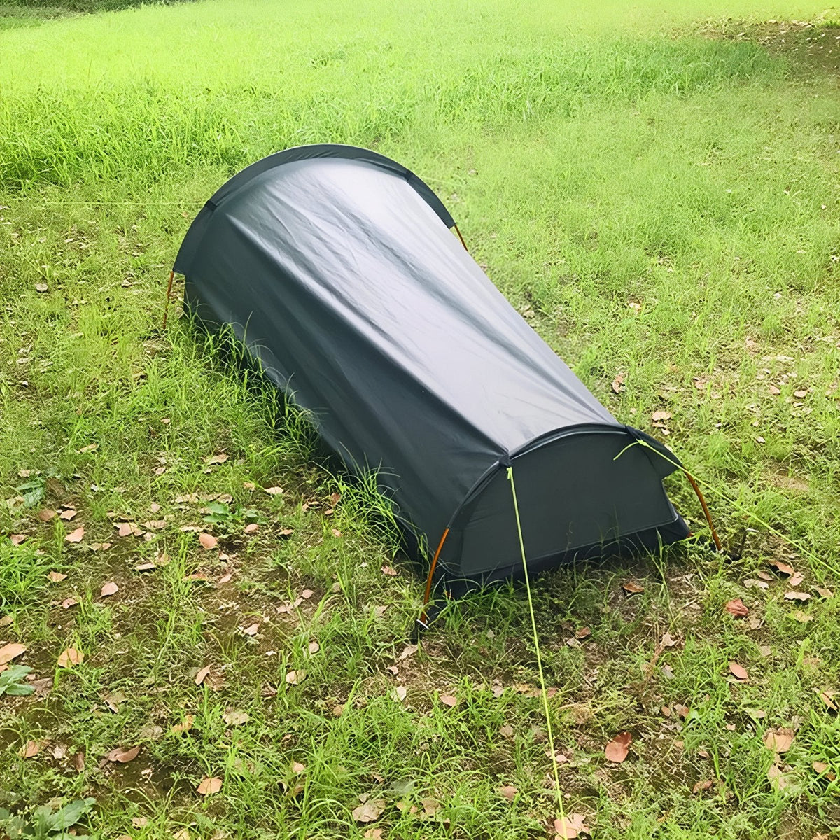 Bivy tent pitched in long grass, seen from the foot end