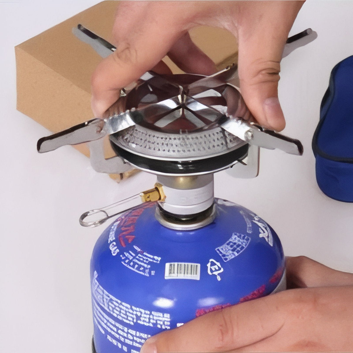 Hands setting up the stove's pot supports on a gas canister
