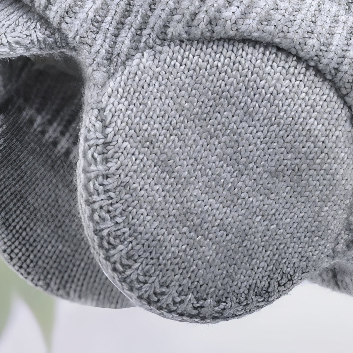 Close-up of a round knitted ear flap on the light grey beanie