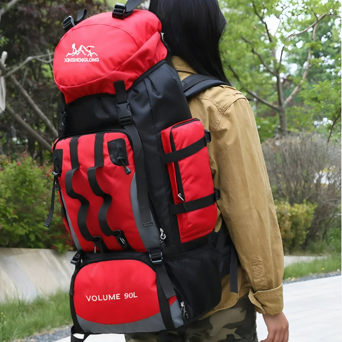 Walker carrying the red 90 L hiking backpack on a park path