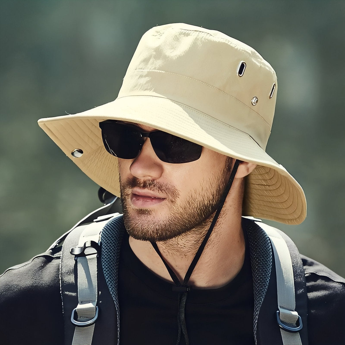 Man wearing the beige wide-brim hiking hat with the chin cord under his chin and sunglasses