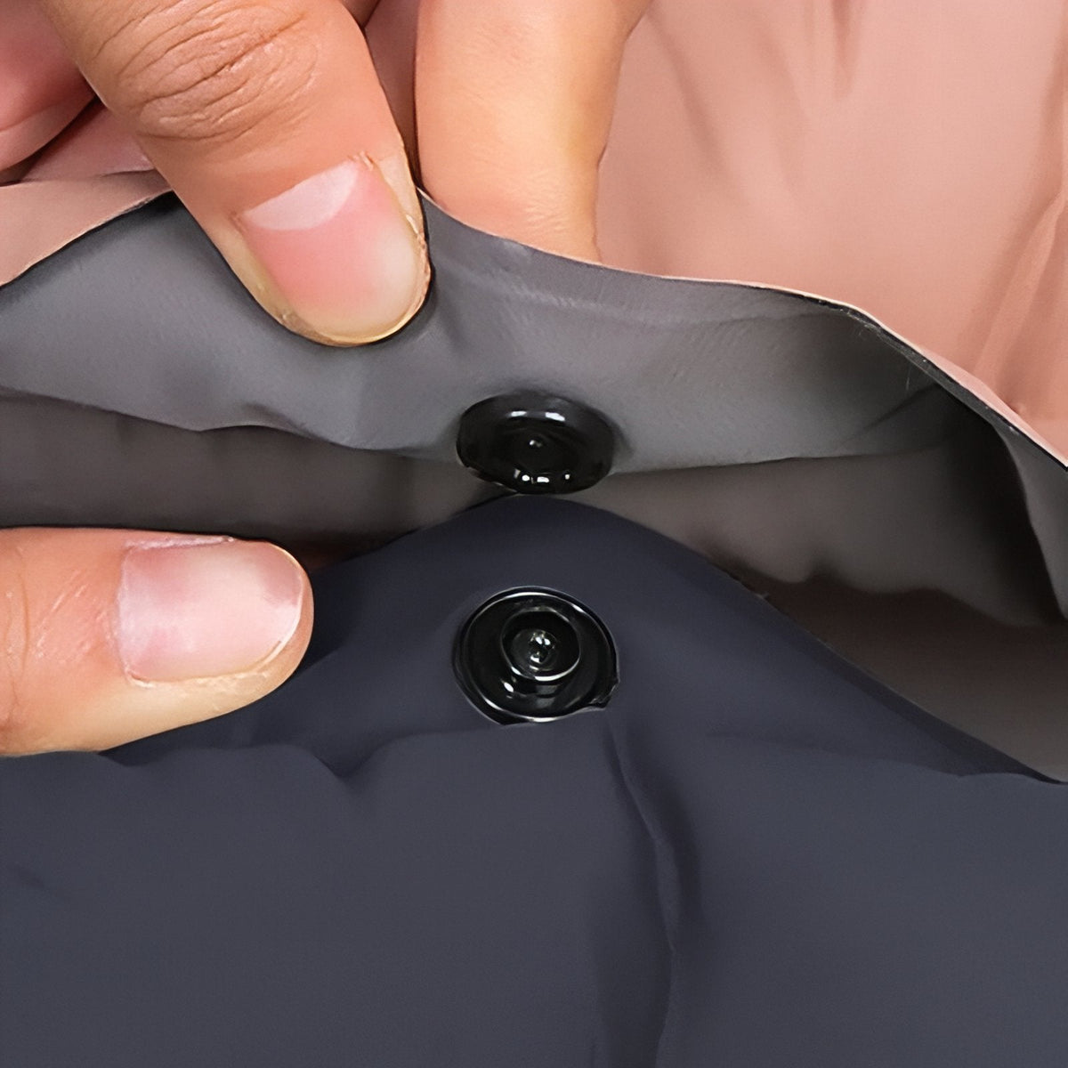 Fingers pressing the snap buttons that join two mats together