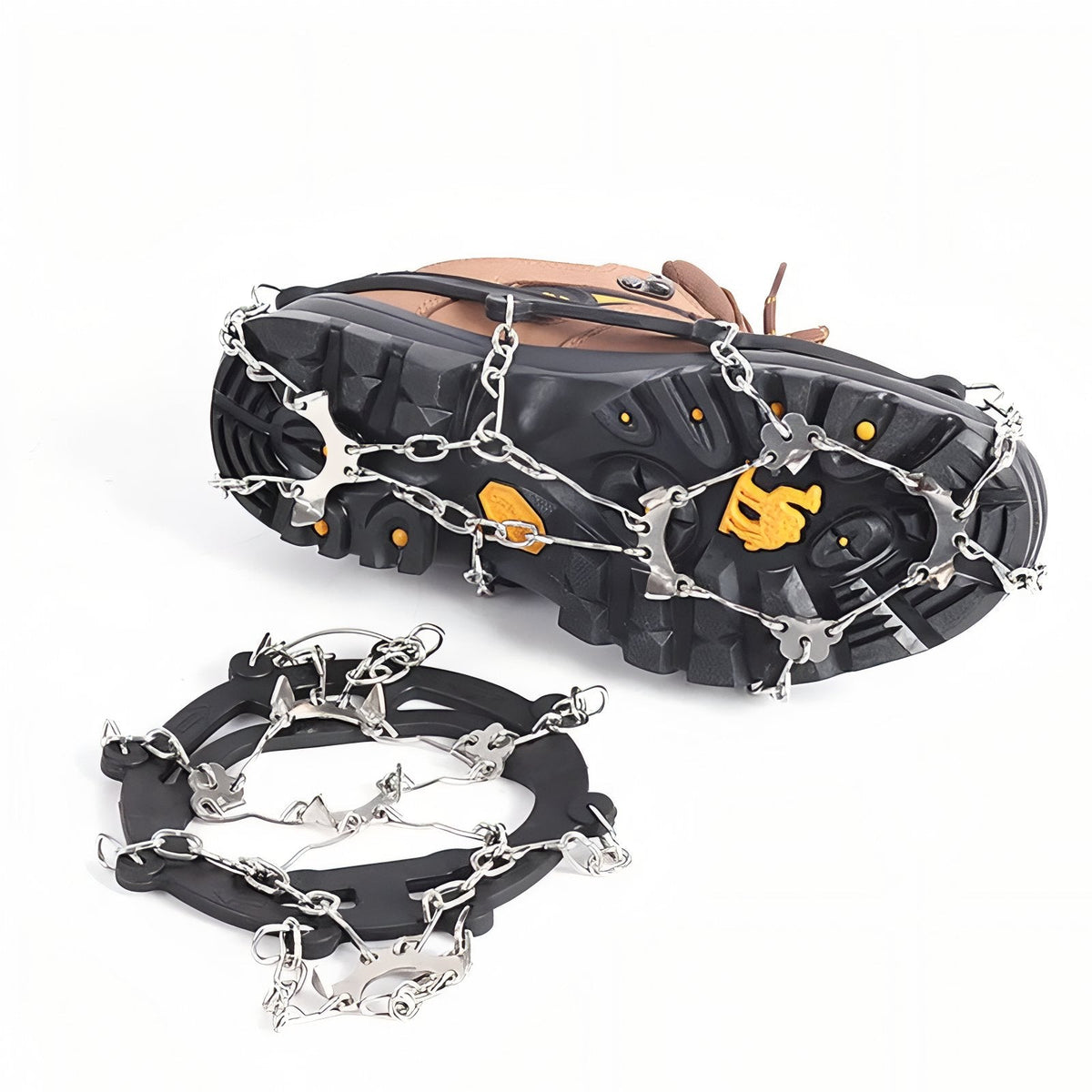 Chains and steel spikes under the sole of a hiking boot, with a black-harness crampon lying in front