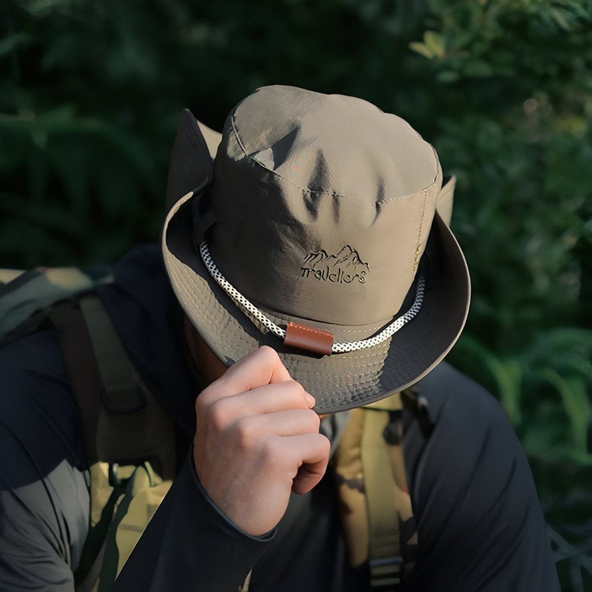 Man tipping the brim of the hiking hat, showing the embroidered crown and braided band