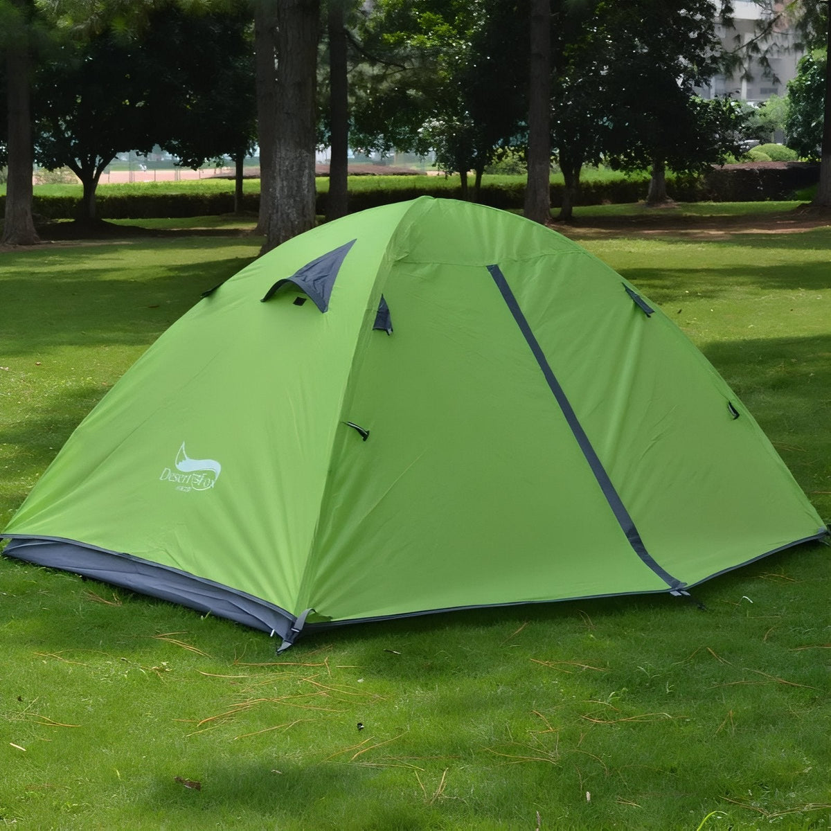 Lime green two-person dome tent pitched on a lawn in a park