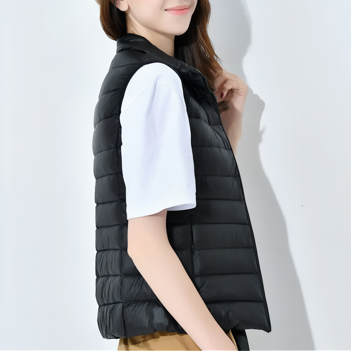 Woman wearing the black quilted vest over a white T-shirt, side view