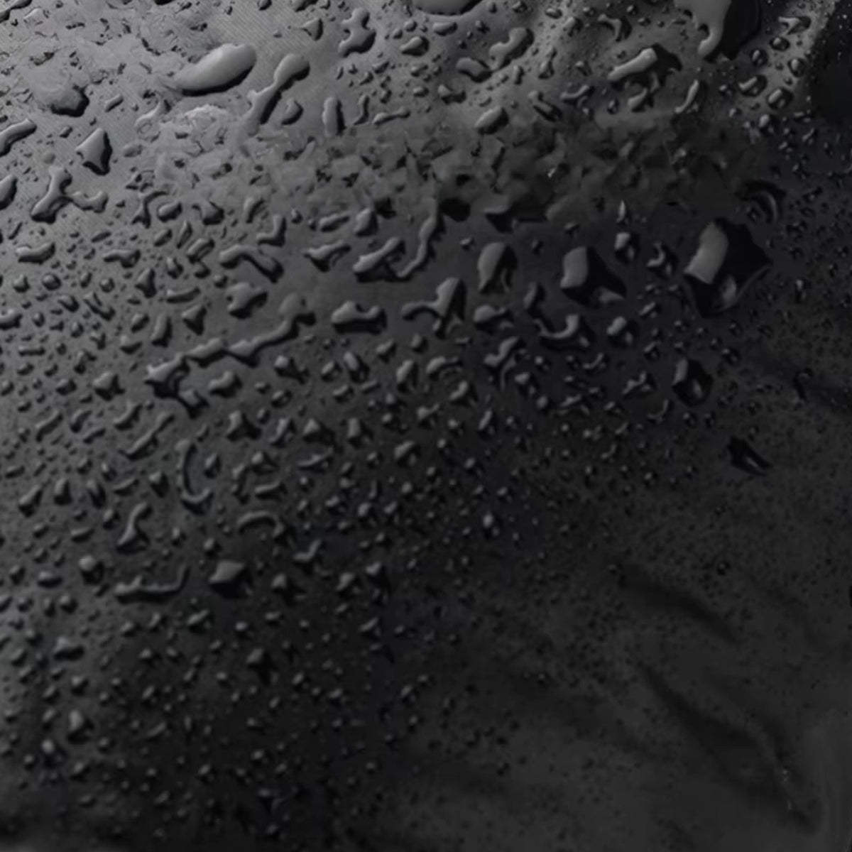 Close-up of water droplets beading on the black nylon outer fabric of the booties