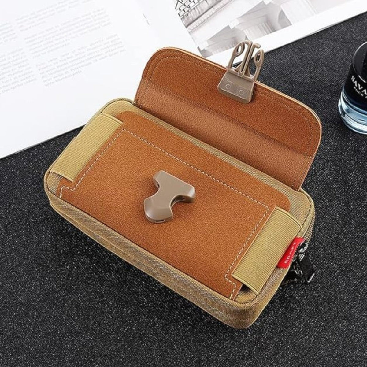 The brown pouch with its flap open, showing the front pocket and the clip buckle