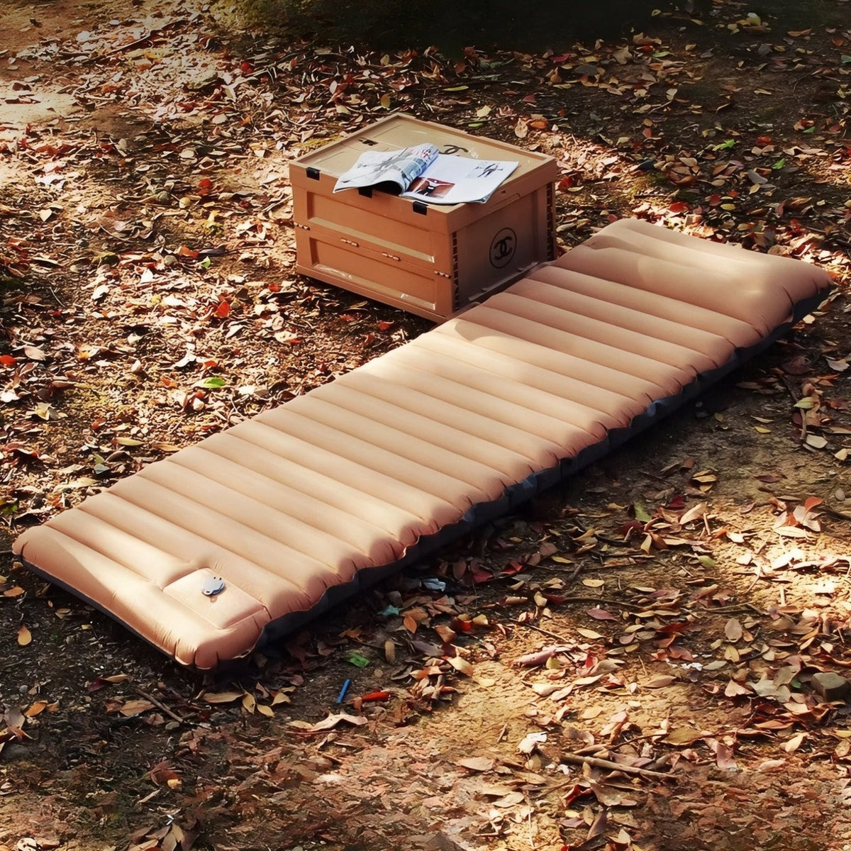 Brown inflatable sleeping mat lying on dry leaves on a forest floor