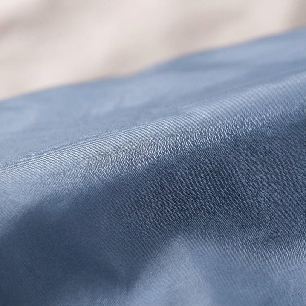 Close-up of the smooth light blue shell fabric of the sleeping bag against its pale lining