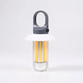 Camping lantern lit, grey clip hook and cap, white shade and clear tube with warm LED strips, on a light grey background
