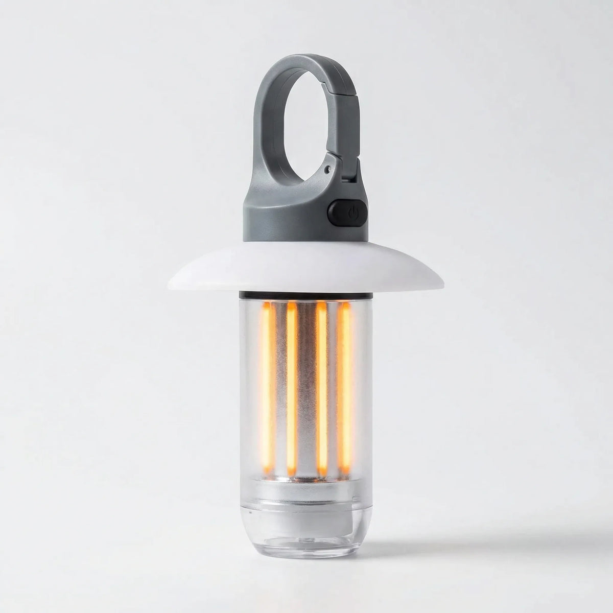 Front view of the lit camping lantern with its grey hook, black button and white shade