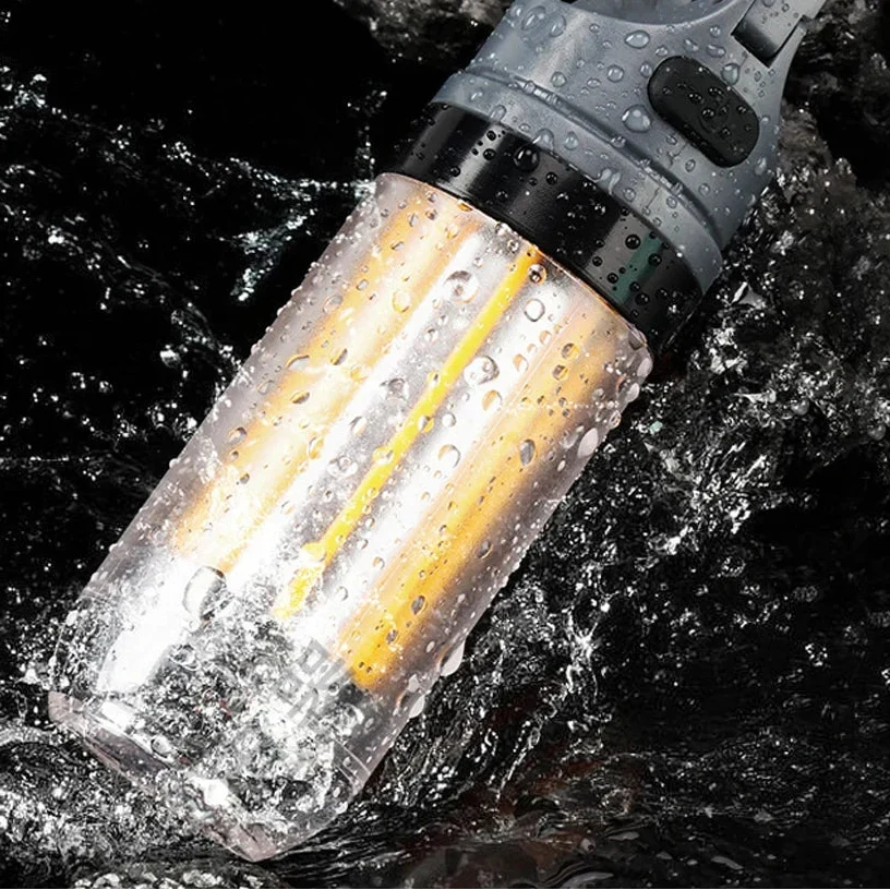 Camping lantern lying in splashing water, droplets on the clear tube