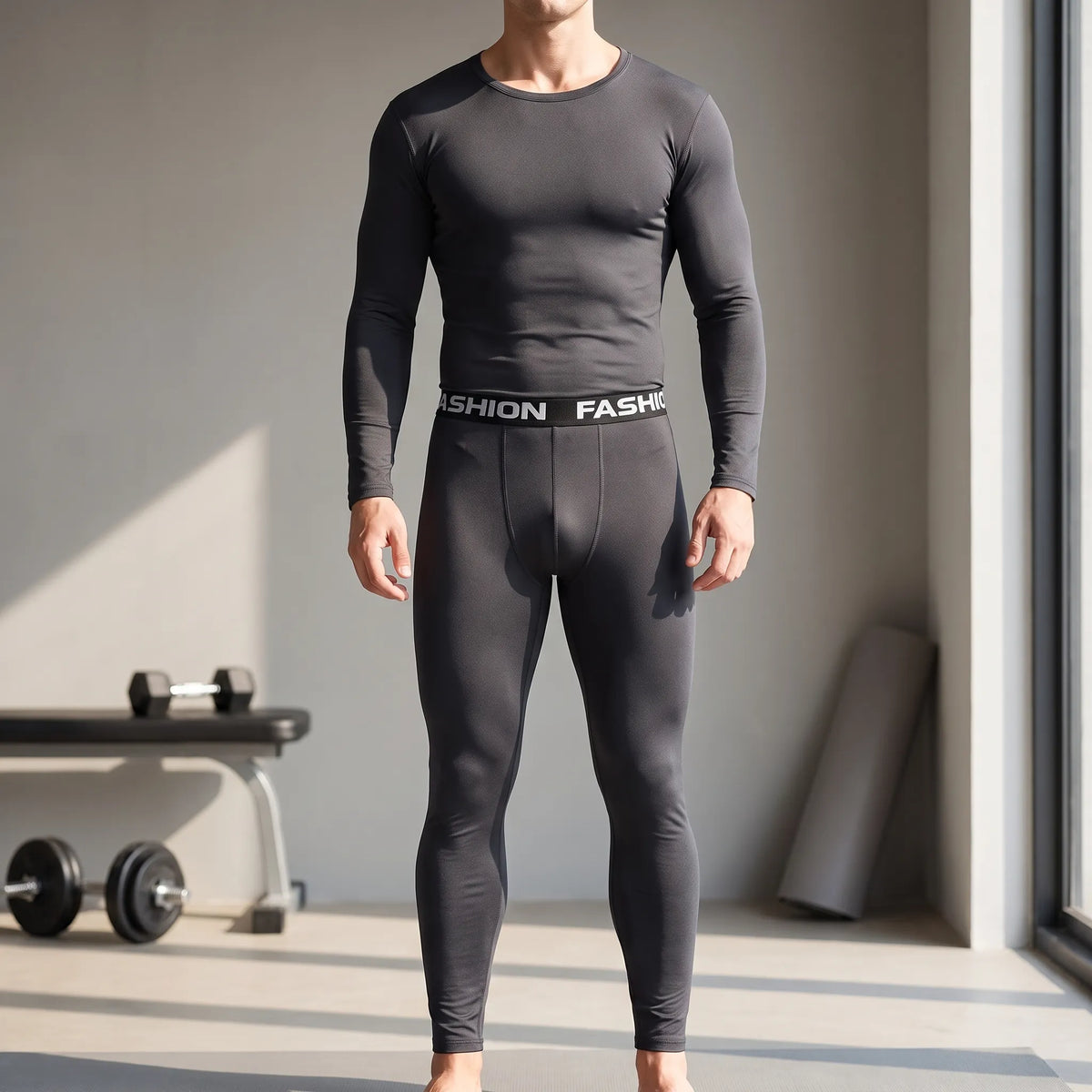 Man wearing the black thermal base layer set, long-sleeved crew-neck top and leggings with a wide printed waistband, standing in a room