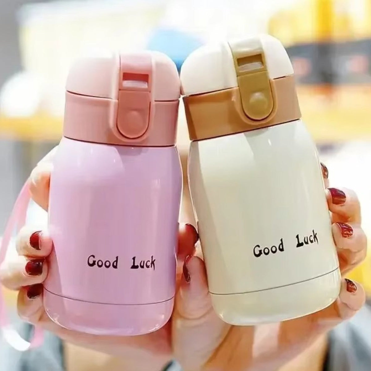 Hands holding up a pink and a cream insulated bottle