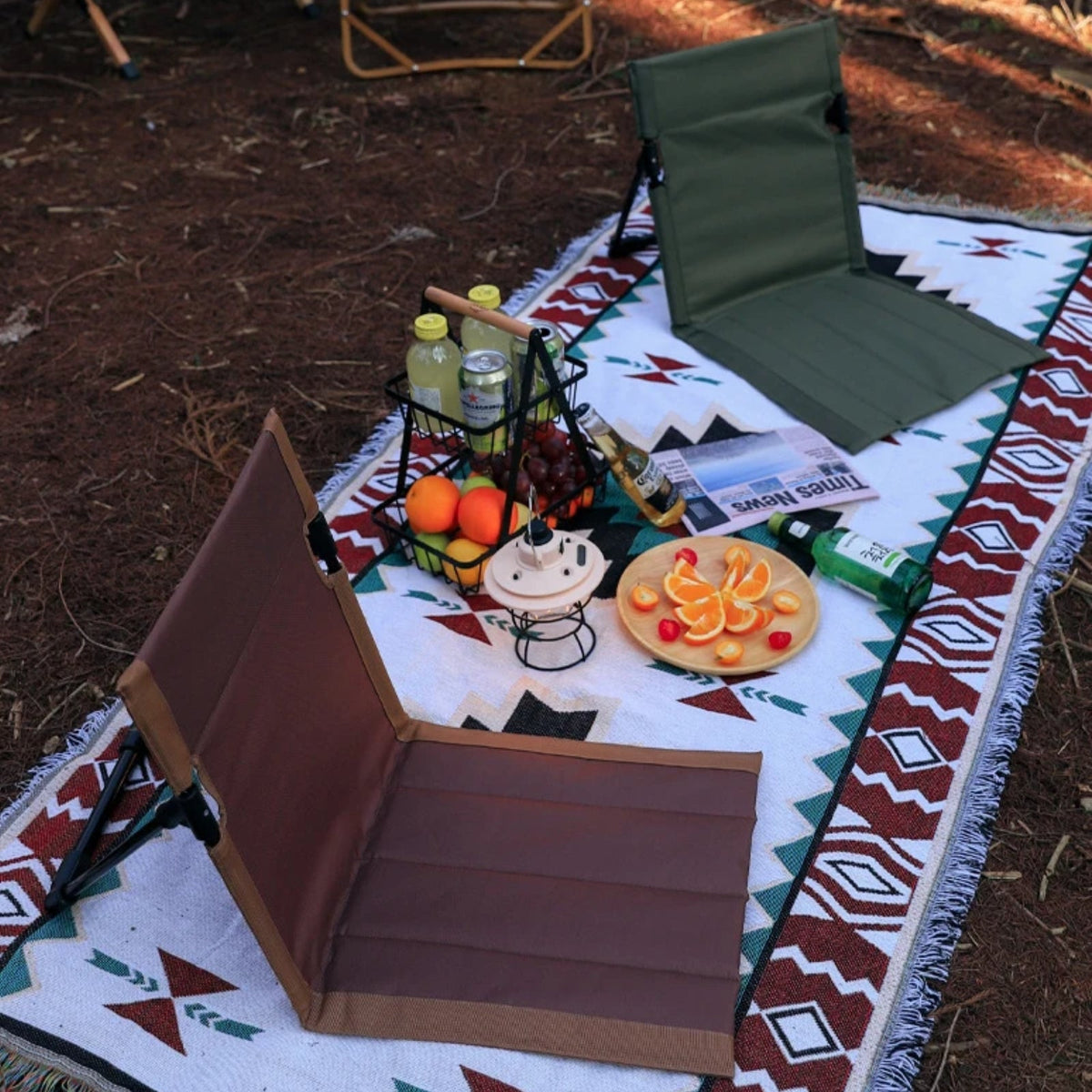 Brown and olive green ground chairs on a patterned picnic rug with fruit