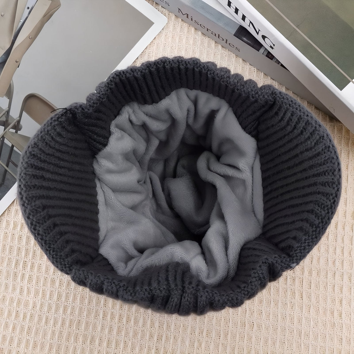 Inside of the black knit beanie turned up, showing the grey plush fleece lining