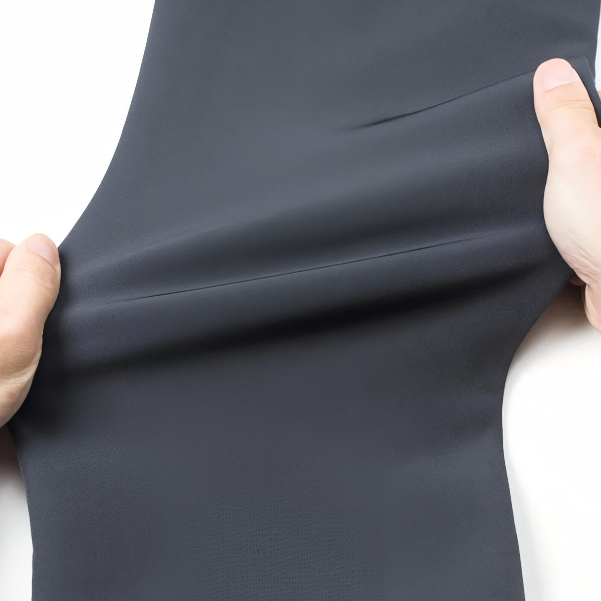 Hands stretching the slate grey softshell fabric of the trousers