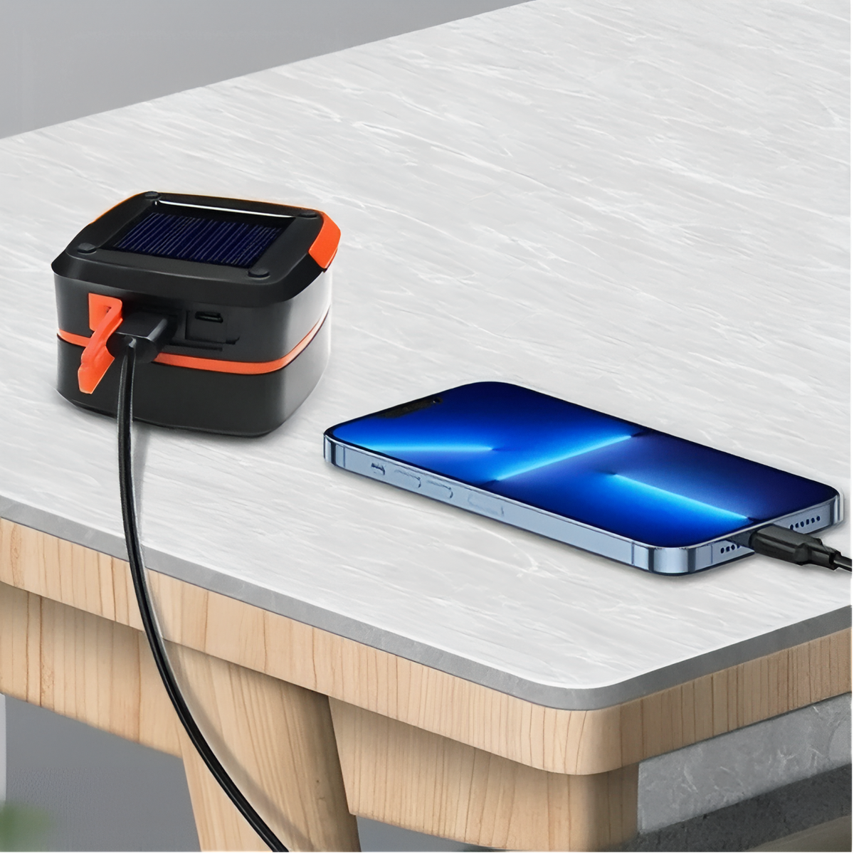 Orange lantern on a table with a phone connected to it by a cable
