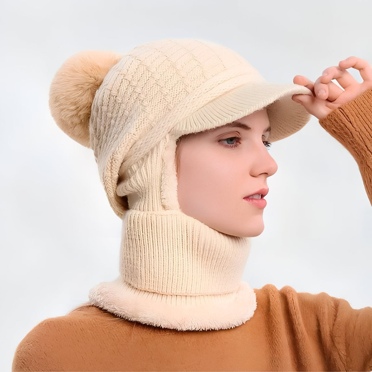 Woman in profile wearing the cream brim beanie with pompom and the neck warmer round her neck
